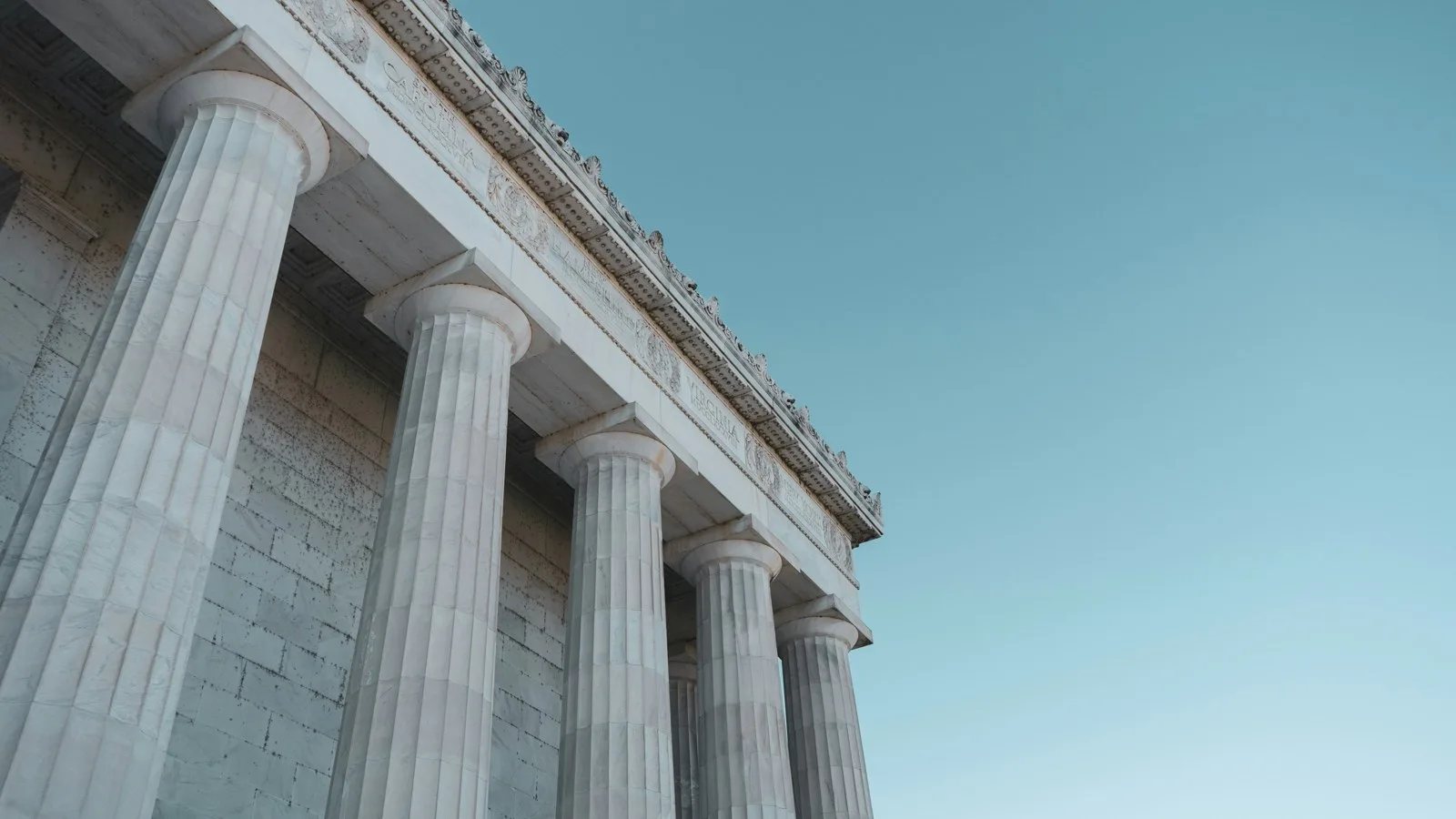 Marble columns of a classical government building rising against a clear blue sky