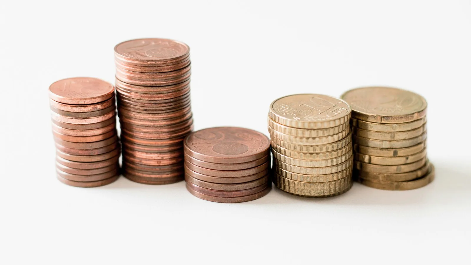 Stacks of copper and gold-colored coins standing in a row on a white surface